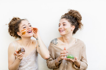 Fashion blogger twins applying face masks, white background
