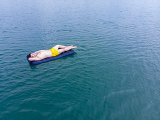 man on mattress in blue water. summer time concept