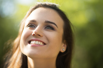Close up photo of cheerful beautiful woman. Portrait of attractive young lady glowing with happines smiling and looking up.