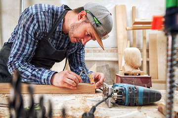 Male carpenter marks of a metal compass and a pencil on a wooden bar for making furniture.