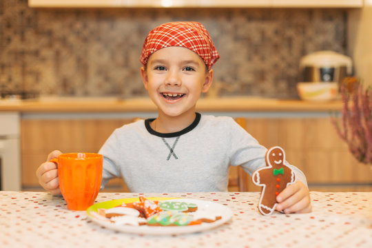 Smiling kid eating gingerbread man with tea on Christmas morning