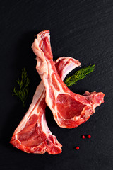 Food concept Organic lamb chops on black slate stone with herbal