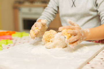 Close-up child hands making dough for biscuits 