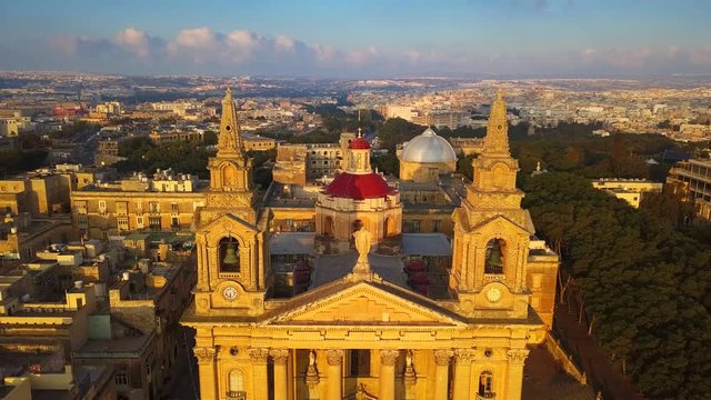 Floriana, Malta - 4K flying away from St. Publius Parish Church at warm sunrise