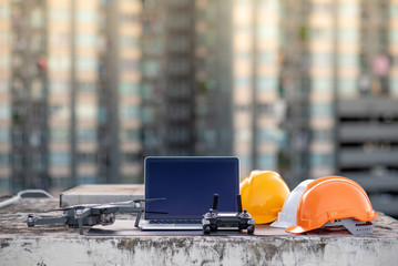 Drone, smartphone, laptop computer and protective helmet at construction site. Using unmanned...