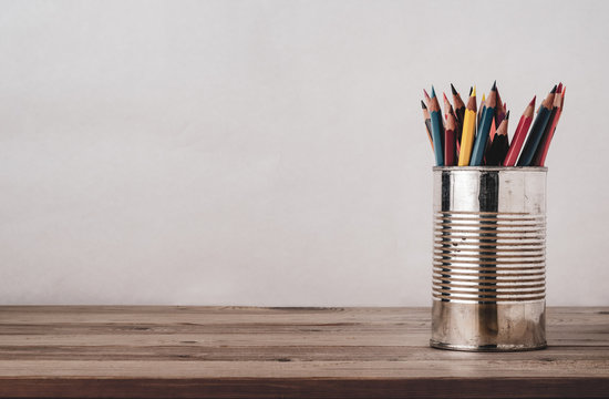 Coloured Drawing Pencils in Metal Tin on Wood Plank Desk