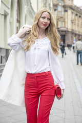 Fashionable young blonde in a spring fashionable suit and with a shopping bag in the center of Moscow
