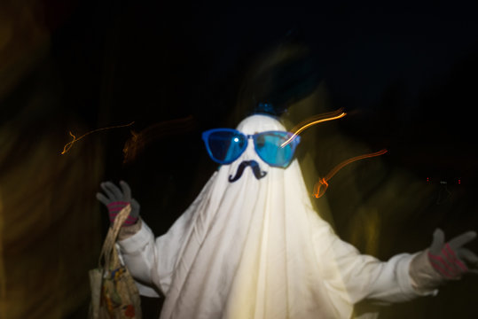 Girl dressed as ghost with mustache and over sized sunglasses, blurred
