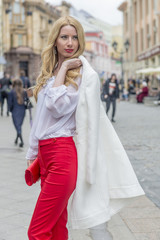 Obraz premium Fashionable young blonde in a spring fashionable suit and with a shopping bag in the center of Moscow 