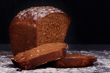испеченный свежий ржаной хлеб в муке на столе на черном фоне