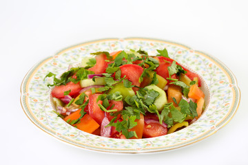 Fresh, healthy and delicious summer vegetable salad with tomatoes, cucumber, green and orange pepper, red onion and parsley