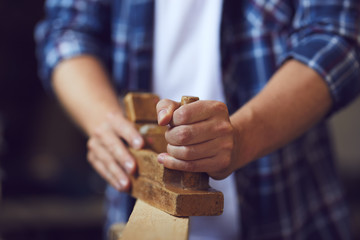 Carpenter working with plane in a carpentry shop