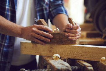 Carpenter working with plane on table in his workshop