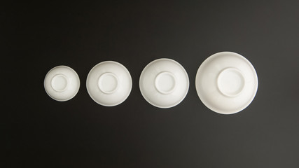set of ceramic kitchen cups inverted on black background, top view