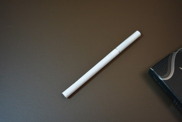 White thin cigarette with ХS filter and packaging on a matte brown background