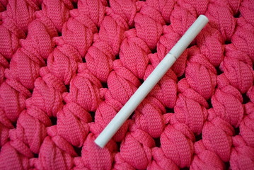 White thin cigarette with filter xs on a pink background