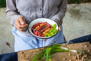 Woman hands holds spicy red beetroot Israeli chickpea hummus with herbs and covered with olive oil. Traditional mediterranean food used with vegetables. Vegan vegetarian healthy food.