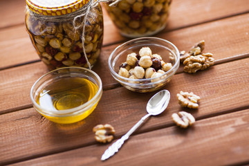 Natural honey and nuts in glass jars, vintage silver spoon on the wooden background. Healthy food, diet, lifestyle concept. Top view. Close up.