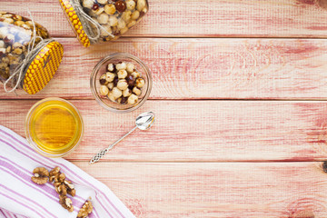 Natural honey and nuts in glass jars, vintage silver spoon on the wooden background. Healthy food, diet, lifestyle concept. Top view. Close up.