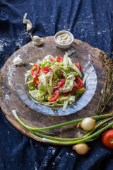 Raw vegan zucchini spaghetti. Yummy fresh summer salad  with red bell pepper, tomatoes, cucumbers and salad leaves garnished and dressed with sesame seeds and homemade tahini dip sauce paste. 