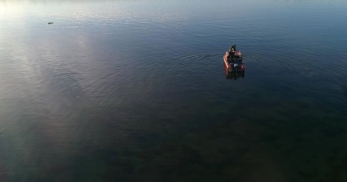 Divers boat , C4K aerial tilt view of a team of divers inspecting the clear waters of baltic sea at a wharf, on a sunny summer evening dusk, in Hanko, Finland