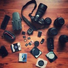 Flat lay design of group of cameras and lens with drone and action camera on wooden background for travel journey concept in vintage tone.