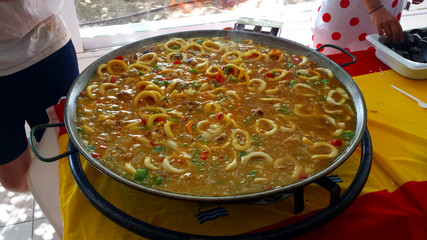 Traditional Spanish paella during cooking on a large metal pan.