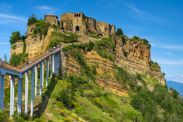 Fototapeta premium Civita di Bagnoregio, Italy - Panoramic view of historic town of Civita di Bagnoregio with a connecting bridge and surrounding hills and valleys of Lazio region