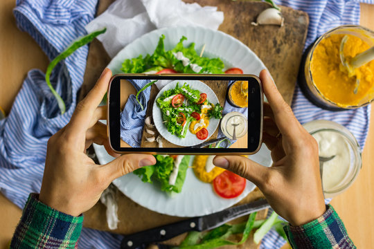 Woman hands take smartphone food photo of vegan spring rolls. Phone food photography for social media or blogging in popular and trendy top view style. Raw vegan vegetarian meal concept.