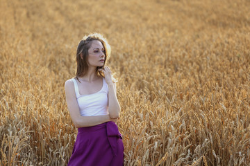 Young beautiful girl standing on wheat field alone