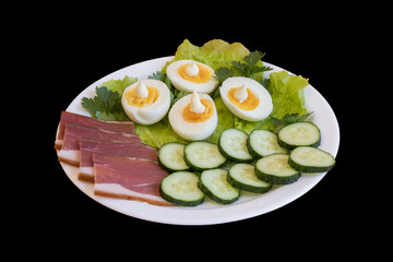breakfast. Boiled eggs, bacon, greens in a white plate isolated on a black background