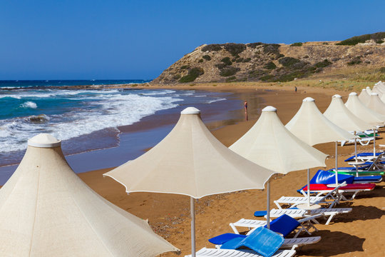 A line of umbrellas and sunbeds in Davlos beach, Cyprus
