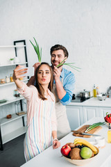 couple taking selfie while having fun during cooking in kitchen