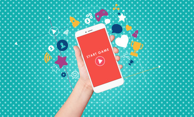 Kid hand holding smartphone with start game button on screen with award and achievement icons on bright blue background. Gamification concept