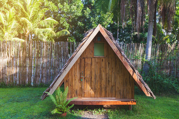Houses made of wood. Bungalow with a roof made of palm leaves against the backdrop of a fence of bamboo and palm trees