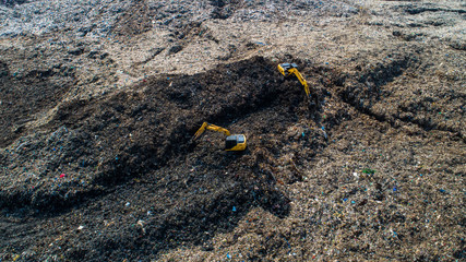 A lot of waste is disposed of in the waste disposal pits. Loaders is working on a mountain garbage. Aerial view and top view.