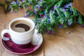 A cup of coffee and a meadow flowers