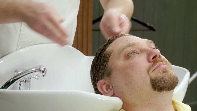 Preparation for haircut. Barber washing men's hair on the head in barbershop. 4K