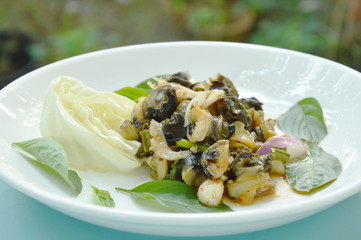 spicy golden apple snail with herb salad on white plate