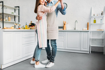 cropped image of couple hugging and dancing in kitchen