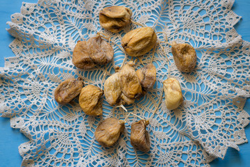 Bunch dried figs on on a knitted napkin on a blue table. Dried fruit.
