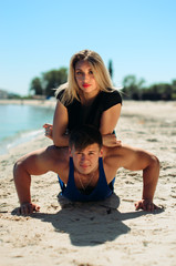 the athlete on the beach posing. the guy pushes from the floor, it is on top of the girl, the exercise of force.