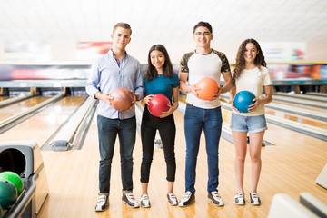 Boys And Girls With Colorful Bowling Balls Standing In Club