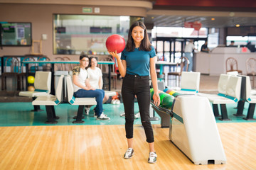 Teenage Girl Holding Bowling Ball At Alley In Club