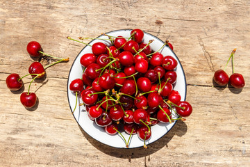 Bowl with fresh ripe cherries on rustic wooden table. Top view