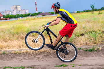 Obraz premium Cyclist riding on the rear wheel of the bicycle, active lifestyle.