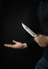 Criminal threatening concept, a bandit with a combat knife trying to rob victim