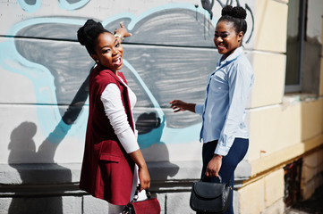 Two stylish african american girls friends with handbags posed outdoor of steets city.
