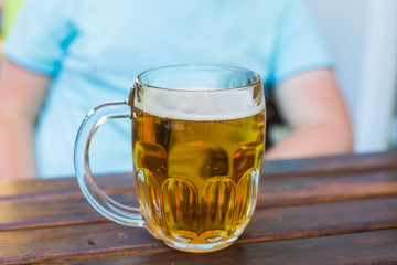 Mug of light beer is on a wooden table in a tavern