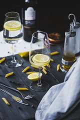 Wine glasses of home lemonade for italian dinner with pasta and peper on the grey wooden background...